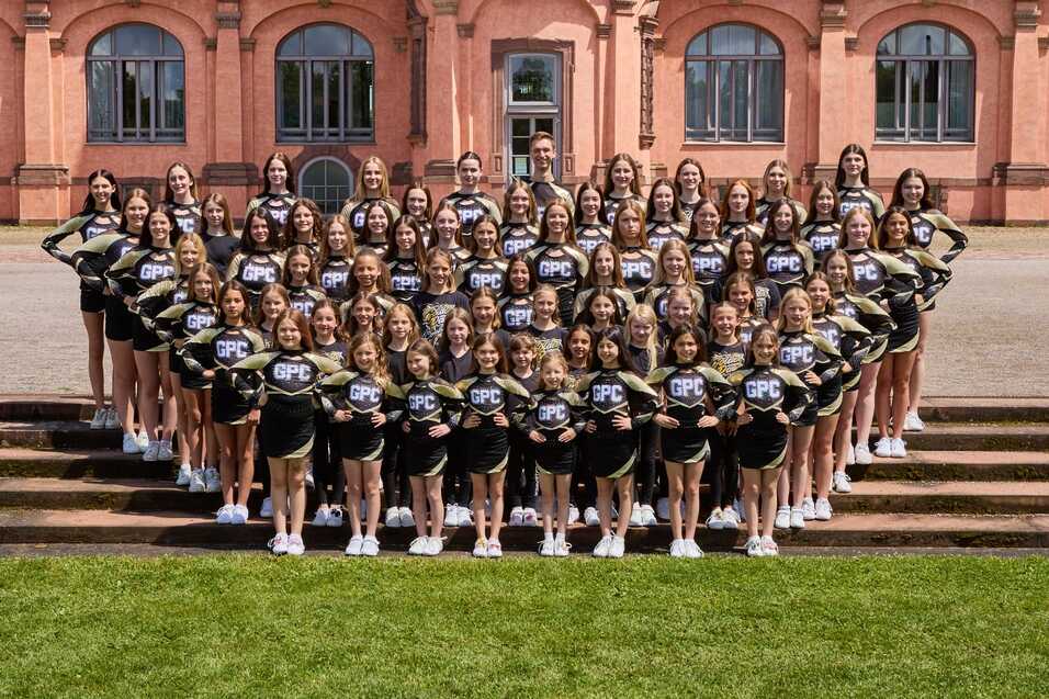 Gruppenfoto von Cheerleadern in einheitlichen Outfits vor einem historischen Geb&auml;ude.